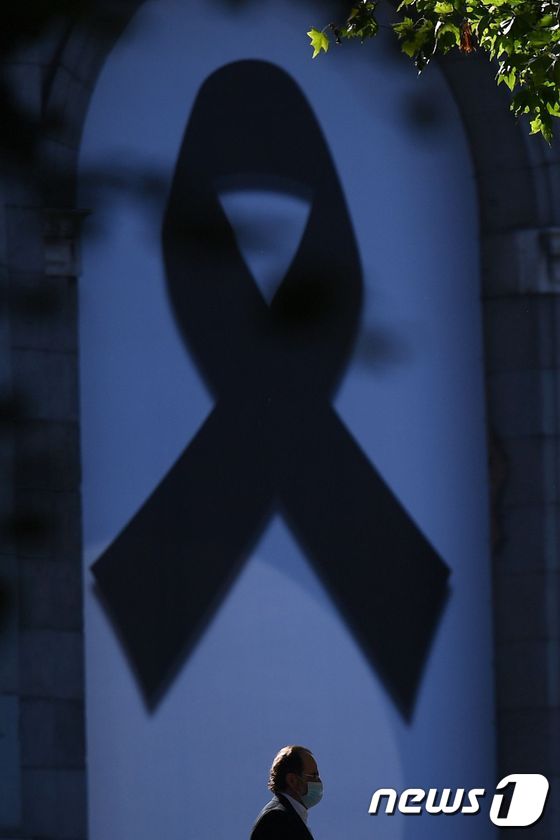 코로나19 희생자를 기리는 검은 리본앞을 한 행인이 지나고 있다. © AFP=뉴스1