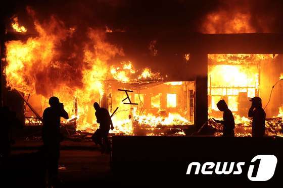 29일 밤 미네소타주 미니애폴리스에서 과격 시위대가 불타는 건물 옆에 서있다. © AFP=뉴스1