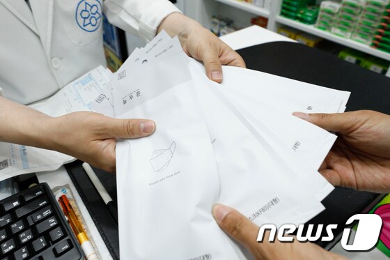 지난 18일 서울시내 한 약국에서 시민이 공적 마스크를 구입하고 있다. 2020.6.18/뉴스1 © News1 안은나 기자