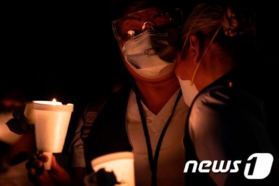 멕시코 바하칼리포르니아주에서 코로나19 감염으로 숨진 간호사를 추모하는 기도회에 참석해 촛불을 들고 있는 의료 관계자들. © AFP=뉴스1