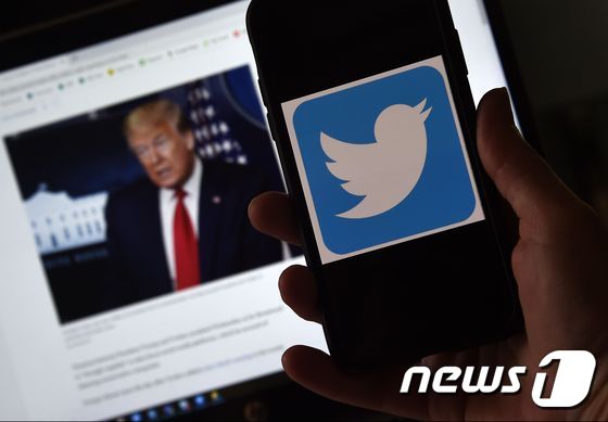 소셜미디어 업체 트위터의 로고 뒤로 도널드 트럼프 미국 대통령의 모습이 보인다. © AFP=뉴스1