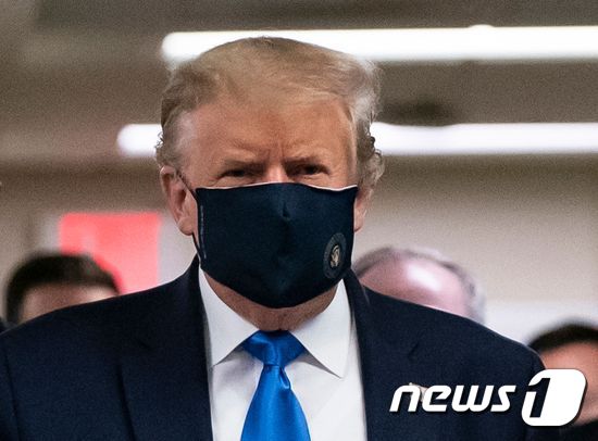 트럼프 대통령은 금색 대통령 인장이 새겨진 남색 마스크를 쓰고 언론사들의 포토존 앞을 지나가며 