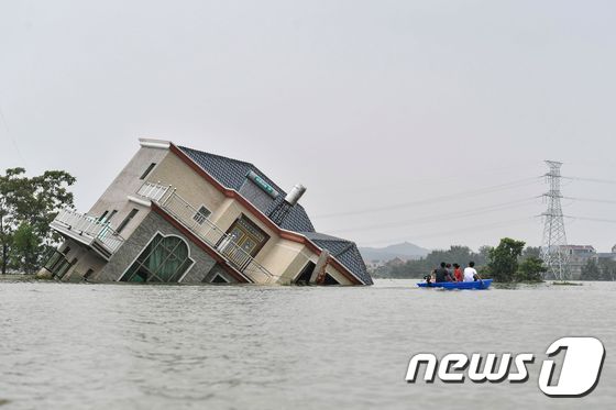 15일 (현지시간) 중국 최대 담수호인 포양호 인근 장시성 상라오에서 주민들이 폭우로 무너진 주택으로 보트를 타고 다가가고 있다. © AFP=뉴스1 © News1 우동명 기자