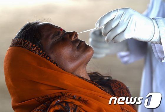 인도 뉴델리의 한 여성이 보건당국 직원에게 코로나19 검사를 받고 있다. © AFP=뉴스1
