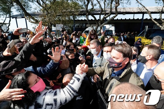 지난달 31일 자이르 보우소나루 브라질 대통령이 마스크를 쓴 채 리오그란데도술주에 방문해 지지자들에게 환영받고 있다.© 로이터=뉴스1