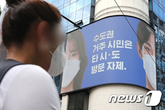 23일 서울 중구 명동거리에서 한 시민이 전광판에 나오는 마스크 쓰기 캠페인 화면 앞을 지나고 있다. 2020.8.23/뉴스1 © News1 임세영 기자