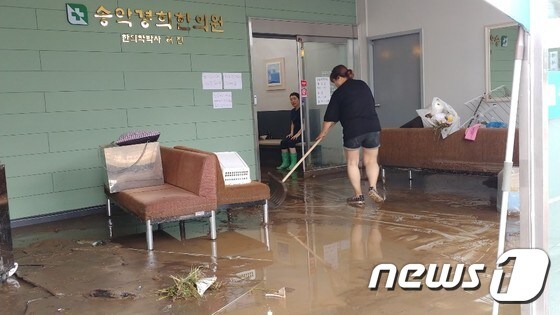 시간당 최대 90㎜내외의 폭우가 쏟아진 충남 아산 송악면 외삼리에 위치한 한의원 직원들이 건물 안까지 들이친 빗물을 빼내고 있다. © 뉴스1