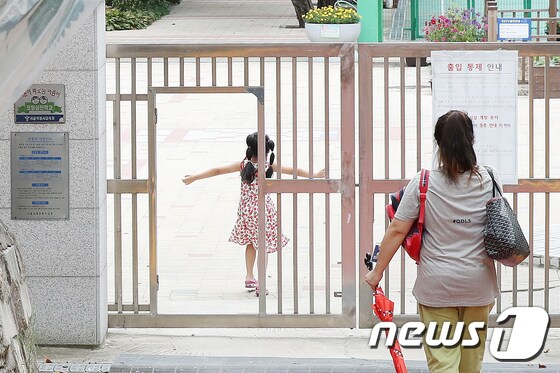 서울 한 초등학교에서 지난 16일 어머니가 자녀를 오후 돌봄교실에 바래다주고 있다. /뉴스1 © News1 민경석 기자