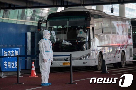 코로나19 기원을 추적하기 위한 세계보건기구(WHO) 전문가팀이 지난 14일 우한 국제공항에 입국했다. 사진은 보호복을 입은 중국 보건요원이 전문가팀이 탄 버스를 지키고 있는 모습. © AFP=뉴스1