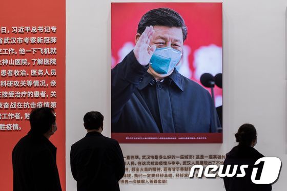 중국인들이 코로나19 방역 전시관에 걸린 시진핑 중국 국가주석의 사진을 관람하고 있다. © AFP=뉴스1