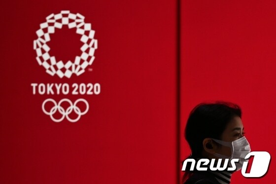 일본 도쿄올림픽 로고 앞으로 마스크를 착용한 시민이 지나가는 모습. <자료사진> © AFP=뉴스1