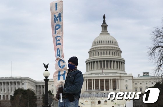 8일(현지시간) 한 남성이 미국 워싱턴DC 연방의회 의사당 근처에서 '탄핵'이라고 적힌 플래카드를 들고 있다. © AFP=뉴스1