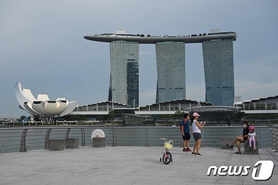 13일(현지시간) 싱가포르 마리나베이샌스 호텔(오른쪽)과 아트사이언스 박물관(왼쪽)이 보이는 공원에서 사람들이 사진 촬영을 하고 있다. 2021.10.13 © AFP=뉴스1