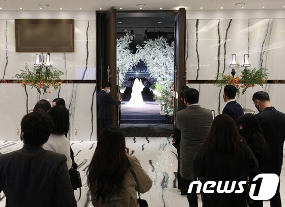 17일 서울의 한 예식장에서 시민들이 식장 밖에서 결혼식을 바라보고 있다. 새로운 사회적 거리두기 조정안에 따라 오는 18일부터 결혼식은 3~4단계에서 식사 여부에 관계없이 최대 250명까지 참석 가능하다./뉴스1 © News1 신웅수 기자