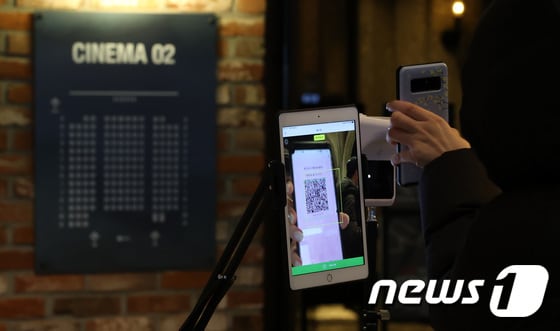 지난 13일 오전 서울시내 한 영화관을 찾은 시민들이 영화 관람에 앞서 QR코드 인증을 하고 있다. 2021.12.13/뉴스1 © News1 조태형 기자