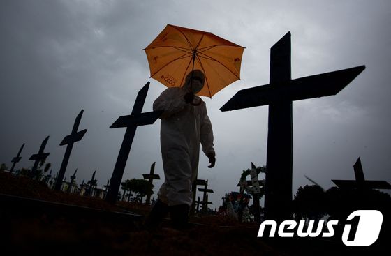 브라질 마나우스의 노사 아파레시다 공동묘지에 2021년 2월 25일 방호복을 입은 인력이 코로나19 희생자들의 무덤을 지나가고 있다. 브라질의 코로나19 누적 사망자 수는 25만여 명에 달한다. © AFP=뉴스1