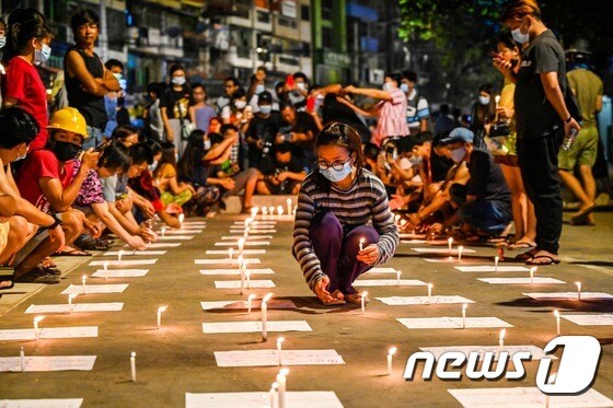 14일(현지시간) 미얀마 양곤에서 군사 쿠데타를 규탄하는 집회 중 시민 시민들이 촛불을 놓고 있다. © AFP=뉴스1 © News1 우동명 기자
