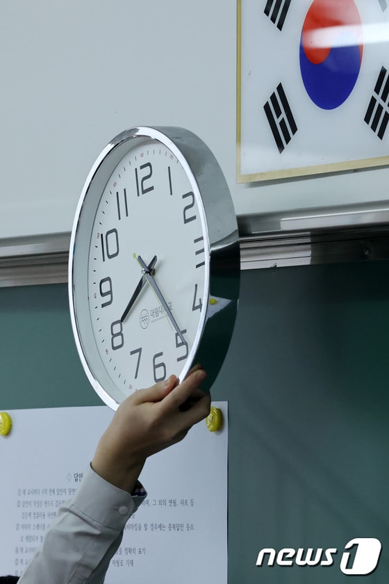 지난 3월25일 경기 소재 한 고등학교에서 3학년 학생이 2021년 3월 전국연합학력평가에 앞서 시계를 옮기고 있다./뉴스1 © News1