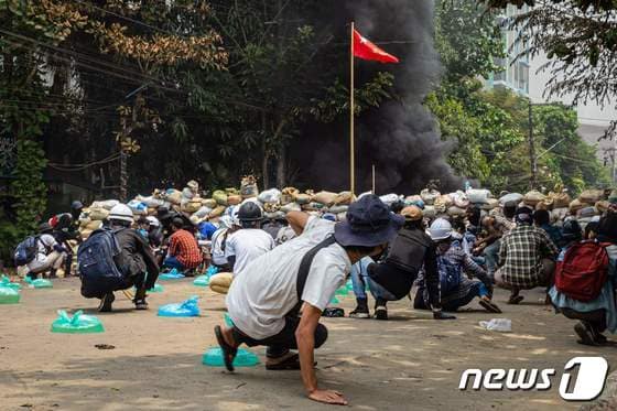 지난달 30일 (현지시간) 미얀마 양곤에서 군사 쿠데타에 반대하는 시위대가 군경과 충돌 중 바리케이드 뒤로 피하고 있다. © AFP=뉴스1 © News1 우동명 기자