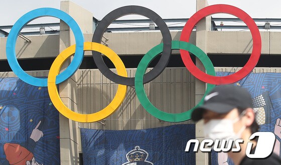 도쿄올림픽 개최를 100여일 앞두고 있는 13일 서울 송파구 잠실주경기장 오륜마크 앞으로 시민들이 지나고 있다. 교도통신에 따르면 지난달 10~12일 실시된 여론조사에서 일본 국민의 70% 이상이 올림픽 취소나 연기를 바란다는 조사 결과 나왔다. 응답자의 39.2%가 올림픽 취소를, 32.8%는 연기를 지지했다. 올림픽을 예정대로 진행해야 한다는 응답자는 24.5%에 불과했다. 이 같은 조사 결과는 최근 들어 일본 국민들 사이에서 코로나19 바이러스 확산 우려가 점점 더 높아지고 있음을 나타낸다. 2021.4.13/뉴스1 © News1 임세영 기자