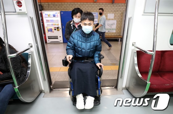 1급지체장애인 여동수(52세)씨가 서울 중구 을지로3가역에서 지하철을 이용하기 위해 활동지원가의 도움을 받으며 열차에 오르고 있다. 2021.4.19/뉴스1 © News1 박세연 기자
