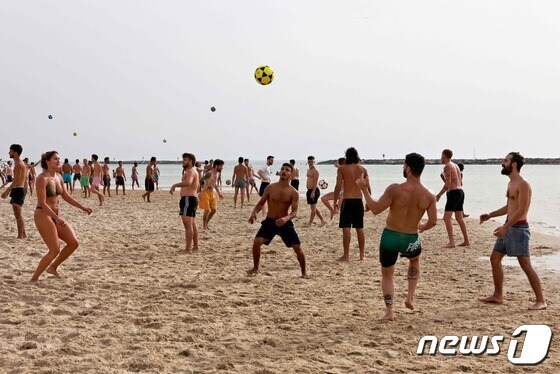 19일(현지시간) 야외 마스크 착용 의무화 해제로 이스라엘 텔아비브 해변에서 시민들이 ‘노 마스크’로 공놀이를 하고 있다. © AFP=뉴스1 © News1