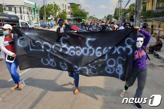 지난 1일(현지시간) 시위대들이 '우리는 민주주의를 원한다'라고 적힌 플랜카드를 들고 양곤 시내를 걷고 있다. © AFP=뉴스1 © News1 원태성 기자
