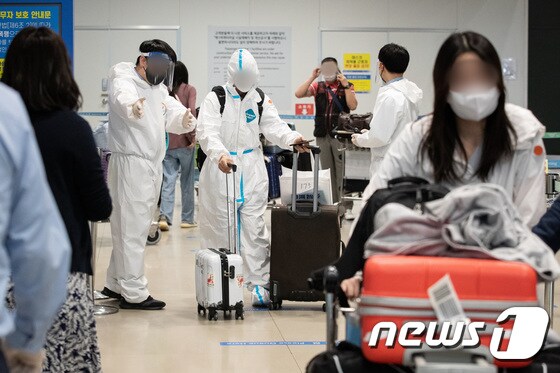 인천국제공항 제1여객터미널 입국장에서 방역관계자들이 입국자들을 안내하고 있다./뉴스1 © News1 유승관 기자