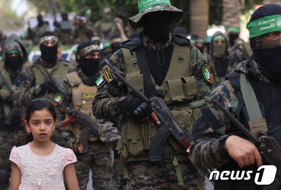 팔레스타인 하마스의 군사 조직 '알카삼 여단'이 행진하는 옆으로 한 어린 소녀가 서있다. © AFP=뉴스1