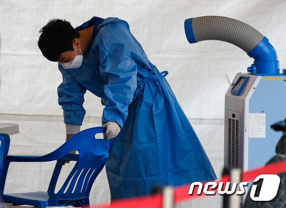 14일 서울역에 마련된 중구 임시 선별검사소에서 더위에 지친 관계자가 냉풍기 바람을 쐬고 있다. 2021.6.14/뉴스1 © News1 안은나 기자
