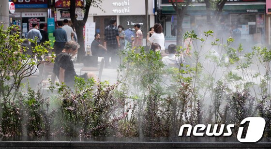 한낮동안 후텁지근한 날씨가 이어지고 있는 24일 서울 중구 명동에서 시민들이 쿨링포그 근처에 앉아 더위를 식히고 있다. 2021.6.24/뉴스1 © News1 유승관 기자