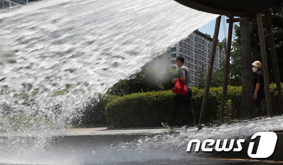 연일 폭염이 지속되는 15일 오후 경기도 수원시의 한 도로에서 수원시청 기후대기과 관계자들이 살수차를 이용해 물을 뿌리고 있다.김영운 기자