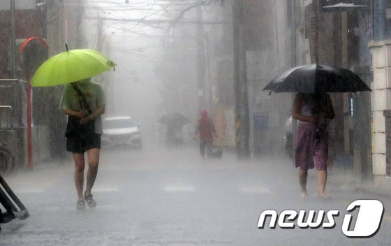 소나기가 내리는 19일 오후 서울 마포구 망원시장 앞 골목에서 우산을 쓴 시민들이 발걸음을 재촉하고 있다. 2021.7.19/뉴스1 © News1 박세연 기자