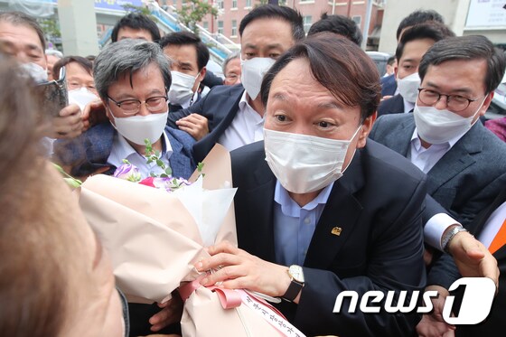 야권 대선주자인 윤석열 전 검찰총장이 20일 낮 대구 서문시장을 찾아 환영의 꽃다발을 받고 있다.  © News1 