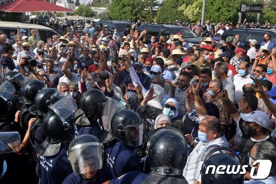 26일(현지시간) 튀니지 수도 튀니스의 국회의사당 앞에서 시위가 벌이는 사람들을 군경이 막아서고 있다.  © AFP=뉴스1