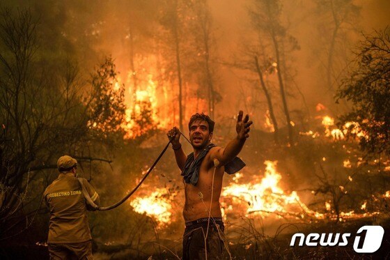 8일(현지시간) 그리스 에비아섬 페프키 마을에서 현지 주민이 산불 진압에 나섰다. © AFP=뉴스1