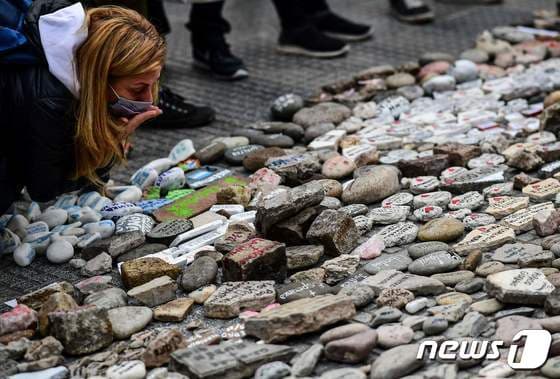 아르헨티나 부에노스아이레스에 있는 대통령궁 카사 로사다 밖에서 시민이 정부 대책에 항의하며 코로나19 희생자들의 이름이 적힌 돌을 놓고 있다. © AFP=뉴스1