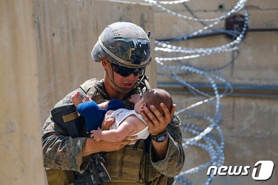 21일(현지시간) 탈레반이 장악한 아프가니스탄의 카불 공항에서 미군이 아프간 아기를 안고 달래며 엄마를 기다리고 있다. © 로이터=뉴스1 © News1 우동명 기자