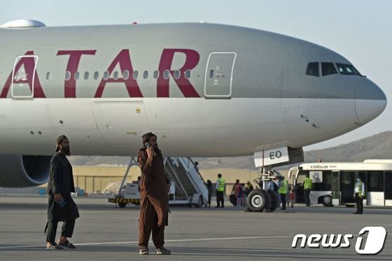 미국인 등 승객 200명이 지난 9일(현지시간) 아프가니스탄 카불 공항에서 카타르 항공기에 오르는 동안 탈레반 조직원들이 경비를 서고 있다. 지난달 30일 밤 11시59분 마지막 미 군 수송기가 떠난 이후 첫 탈출 비행이다. © AFP=뉴스1 © News1 안은나 기자