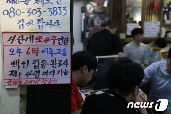 서울 광화문의 한 음식점에서 관계자가 백신 인센티브 관련 문구가 적힌 안내문을 붙이고 있다./뉴스1 © News1 노선웅 기자