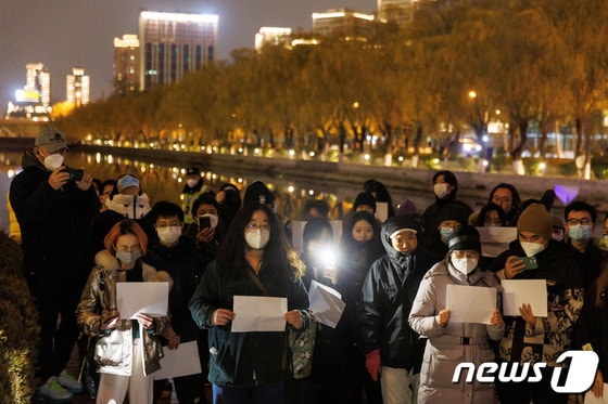 지난 27일 중국 베이징에서 열린 우루무치 화재 희생사 추모 행사에서 사람들이 정부의 코로나19 규제에 항의하기 위해 모여 흰 종이를 들고 있다. 2022.11.28 © 로이터=뉴스1 © News1 김정률 기자