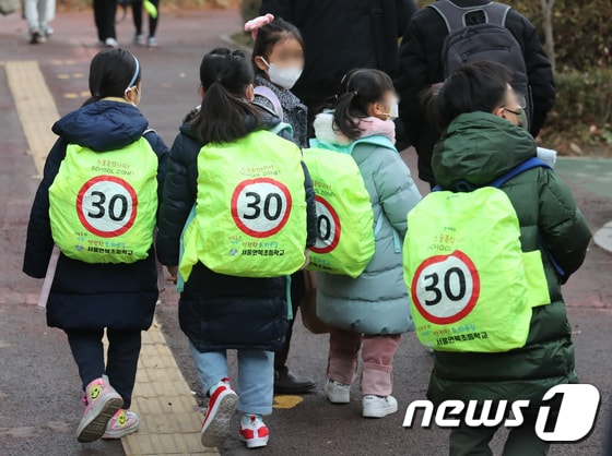 초등학생들이 '스쿨존 입니다' 메시지가 적힌 안전 가방을 메고 등교하고 있다.  © News1 