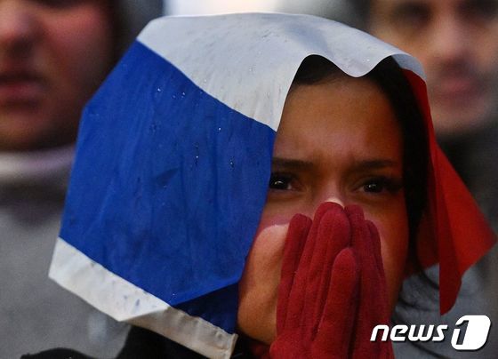 18일(현지시간) 프랑스 파리에서 아르헨티나와 카타르 월드컵 경기 연장전을 지켜보는 한 여성이 머리에 프랑스 국기를 쓴 채 두 손으로 입을 가리고 있다. 2022.12.18 © AFP=뉴스1 © News1 정윤미 기자
