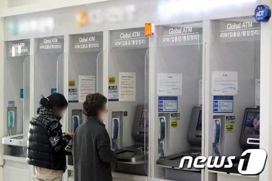 서울 시내 한 건물에 설치된 은행의 현금인출기(ATM)에서 시민들이 입출금을 하는 모습. 2022.12.27/뉴스1 © News1 황기선 기자