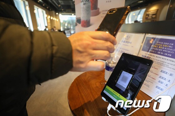 지난 18일 서울 강남의 한 카페에서 시민들이 입장 전 QR코드를 찍고 있다. 2022.2.18/뉴스1 © News1 성동훈 기자