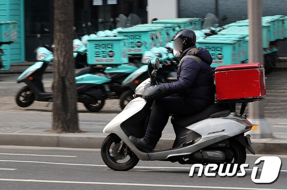 서울 강남구 배민라이더스 남부센터에 배달용 오토바이 앞으로 한 배달 노동자가 지나가고 있다. 1/뉴스1 © News1 박세연 기자