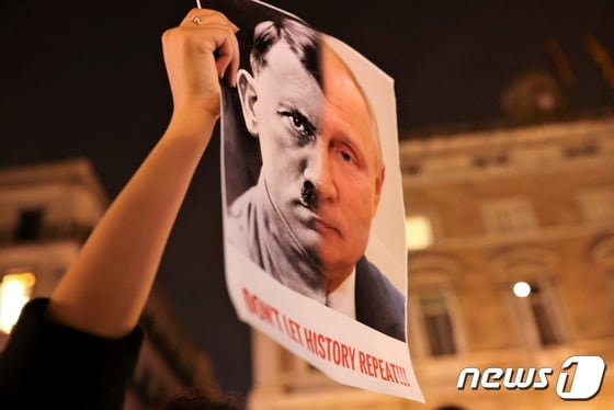 스페인 바르셀로나에서 24일(현지시간) 한 시민이 우크라이나 전쟁을 반대하는 시위를 하고 있다. 시민이 들고 있는 팻말에는 히틀러와 푸틴이 합성된 이미지와 함께 