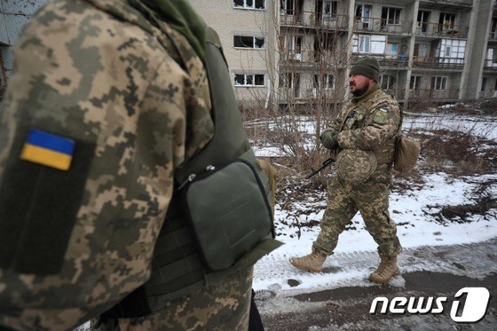 우크라이나 군인들이 2022년 2월 7일(현지시간) 도네츠크주 마린카에서 러시아의 지원을 받는 분리주의자들과 함께 파손된 건물 앞으로 걸어가고 있다. © AFP=뉴스1 © News1 김지현 기자