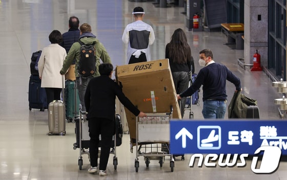 13일 인천국제공항 1터미널에서 해외 입국자들이 방역 요원의 안내를 받으며 이동하고 있다. 2022.3.13/뉴스1 © News1 안은나 기자