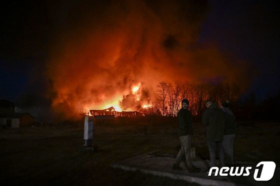17일 키이우에서 러시아 군의 포격을 받아 불 타는 창고 앞에 우크라이나 군이 서 있다. © AFP=뉴스1 © News1 우동명 기자